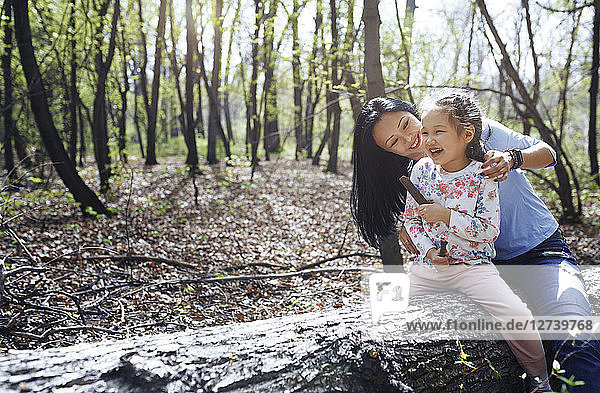 Mother and daughter in park  sitting on tree trunk