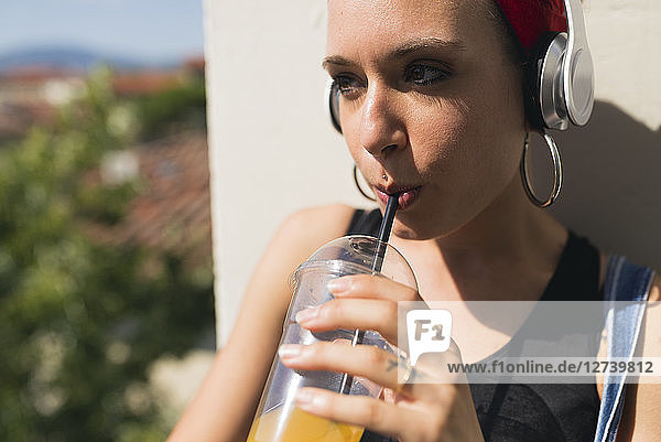 Portrait of young woman with headphones drinking soft drink