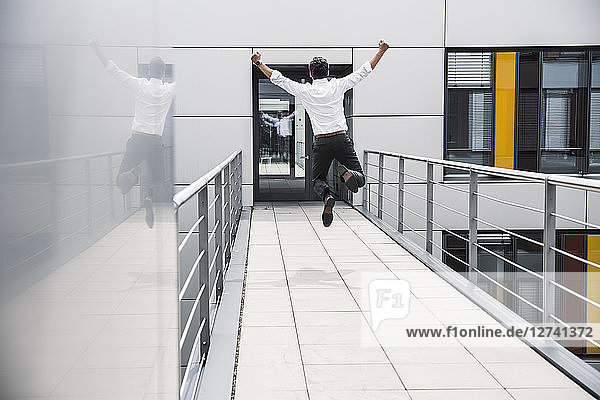 Cheering businessman jumping on skywalk at office building