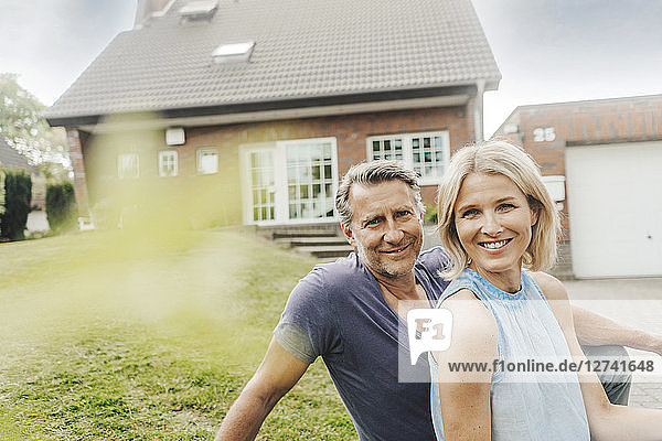 Portrait of smiling mature couple sitting in garden of their home