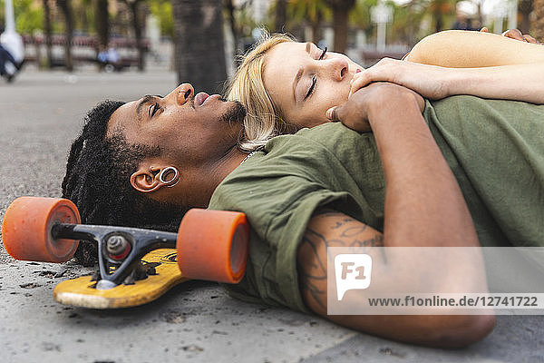 Multicultural young couple with longboard relaxing together