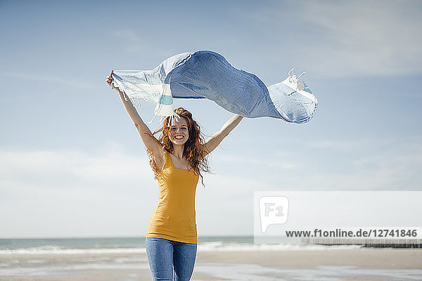 Happy woman having fun at the beach  dancing and swaying towel