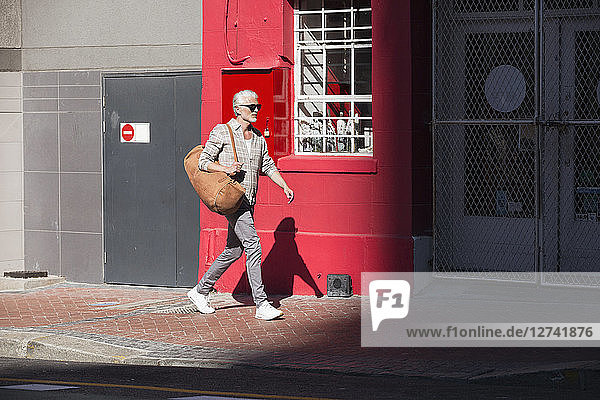 Mature man walking in the city  carrying bag