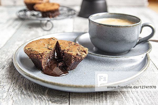 Chocolate muffin with liquid chocolate on plate with coffee cup