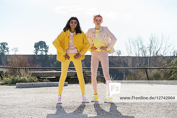 Two alternative friends wearing yellow and pink jeans clothes  posing