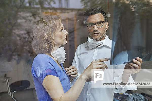 Portrait of radiologist and nurse behind windowpane looking at x-ray image