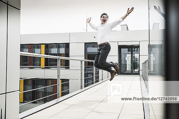 Cheering businessman jumping on skywalk at office building