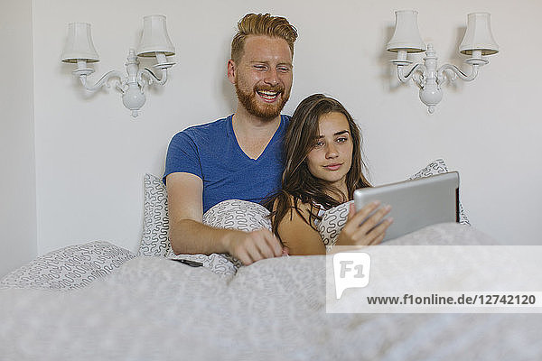 Couple in bed using tablet