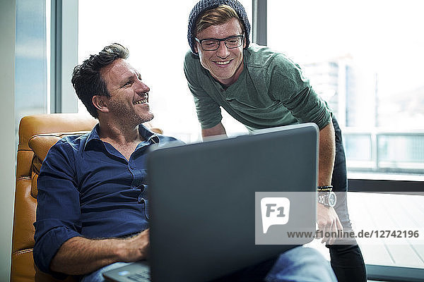 Two man working in modern office  using laptop  sitting in armchair