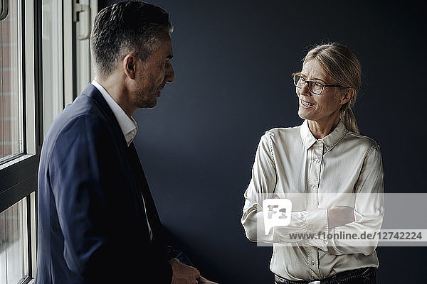 Businessman and businesswoman talking at the window
