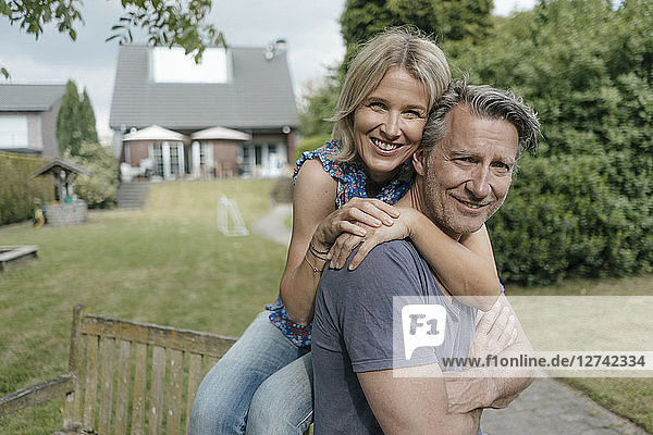 Portrait of smiling mature couple embracing in garden of their home