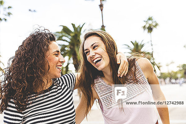 Two happy female friends on promenade with palms