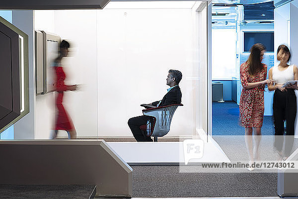 Businessman sitting chair on a busy office floor  working