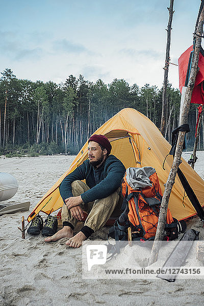 Backpacker sitting in front of his tent on the beach