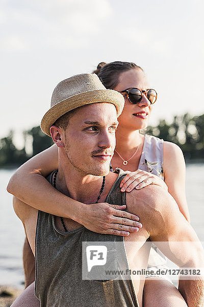 Young man giving girlfriend piggyback ride at the riverbank