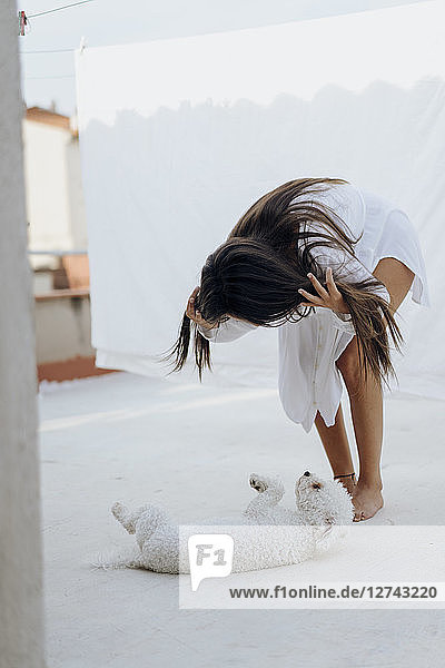 Young woman playing with her dog on roof terrace