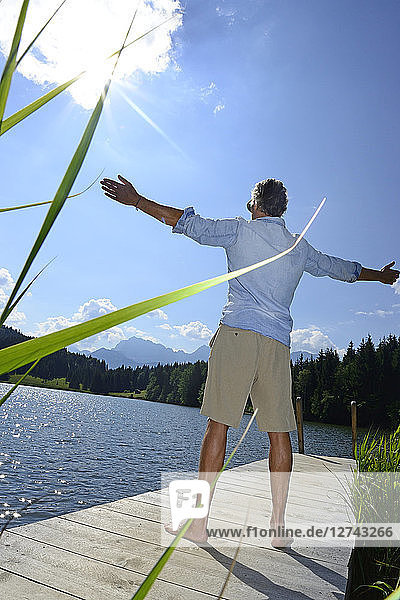 Germany  Mittenwald  back view of mature man standing on jetty at lake