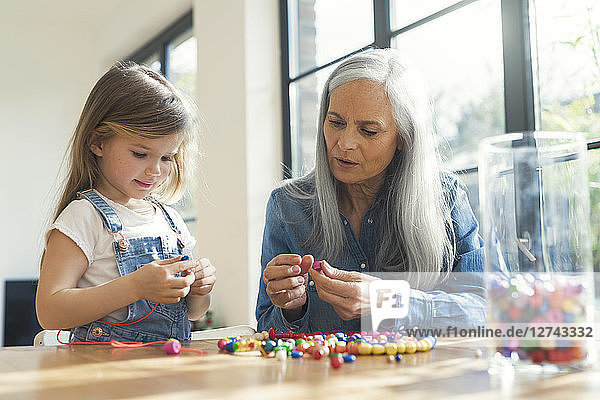 Grandmother and granddaughter threading beads