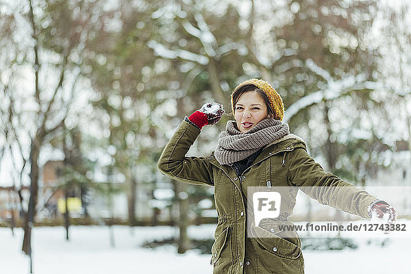 Portrait of woman throwing snowball