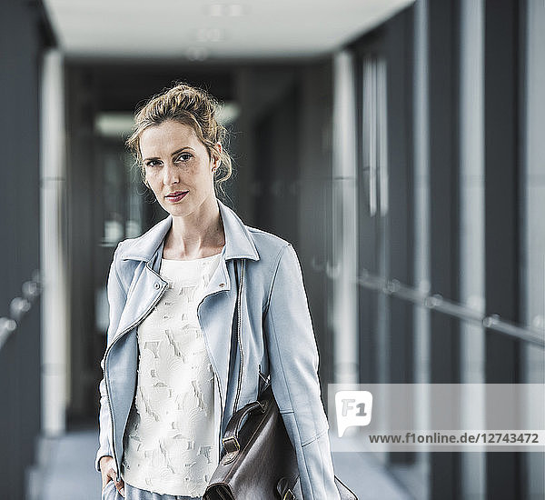 Portrait of confident businesswoman in office passageway