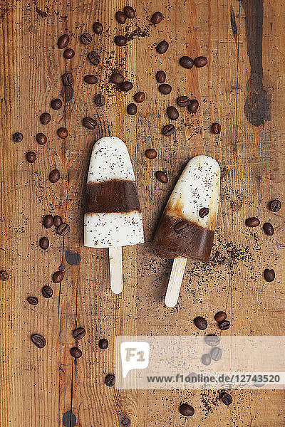 Homemade Espresso-Macchiato ice lollies with coffee beans on wooden background