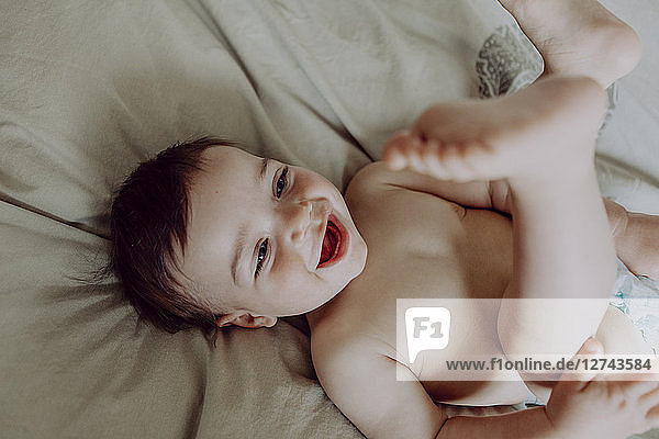 Happy baby  lying on bed  laughing