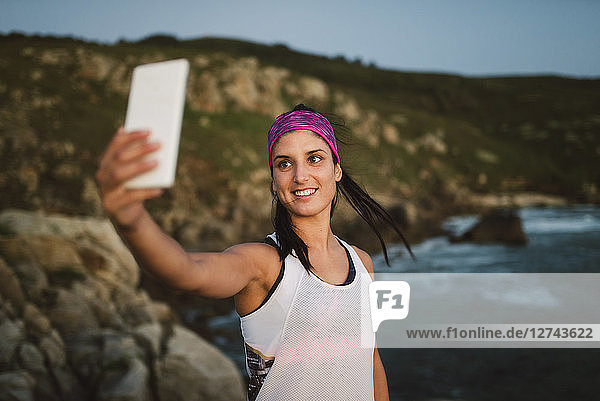 Athlete woman taking a selfie on the coast in the evening
