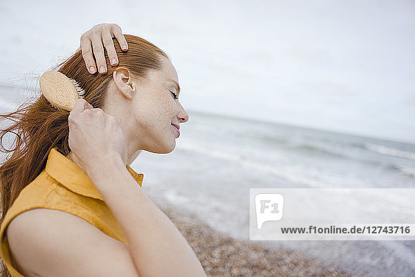 Woman using hair brush at the sea
