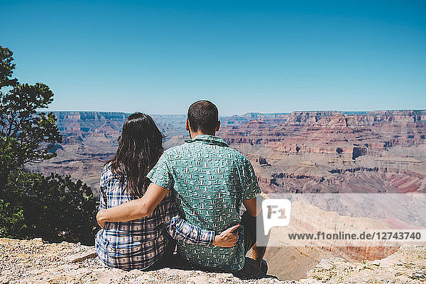 USA  Arizona  Grand Canyon National Park  back view of couple sitting side by side looking at view