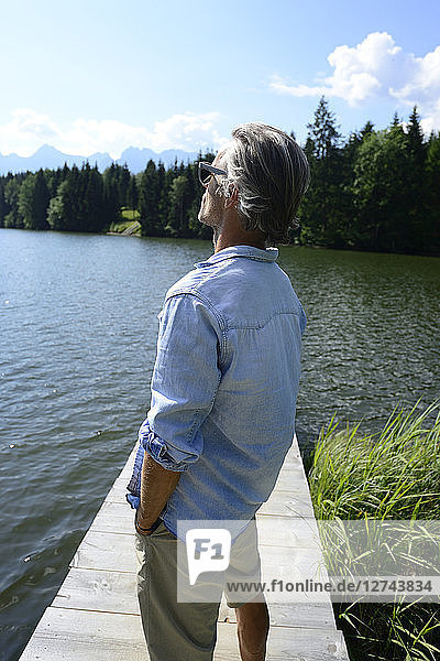 Germany  Mittenwald  mature man standing on jetty at lake relaxing