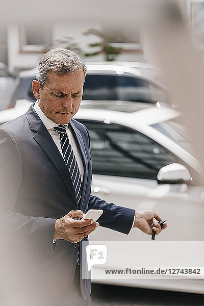 Businessman checking message while using remote control key of car