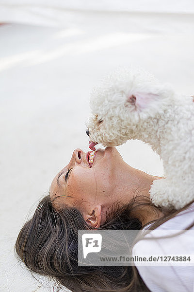 Happy young woman cuddling with dog on roof terrace