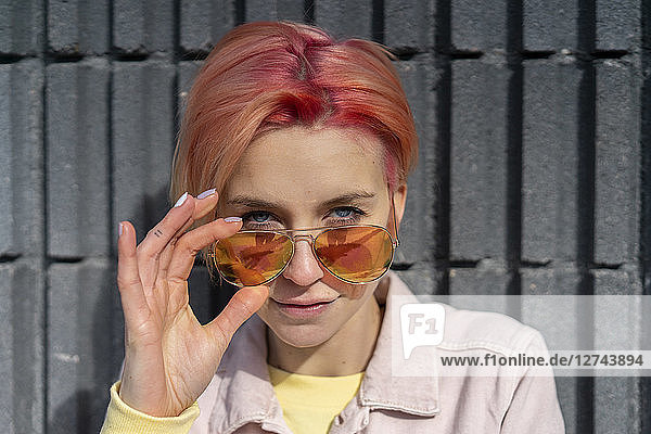Portrait of young woman  sun glasses and pink jeans jacket