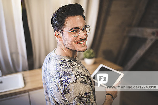 Portrait of smiling young man using tablet at home