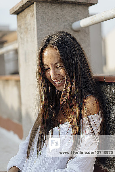Portrait of laughing young woman relaxing on roof terrace