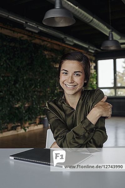 Portait of smiling young woman in office with laptop