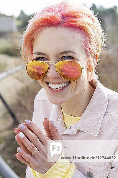 Portrait of young laughing woman  sun glasses and pink jeans jacket