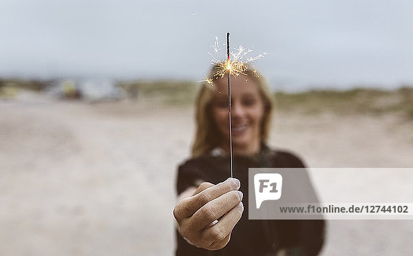 Spain  Aviles  teenage girl holding a sparkler on the beach