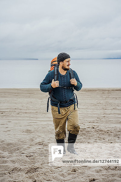 Man with backpack  walking on the beach