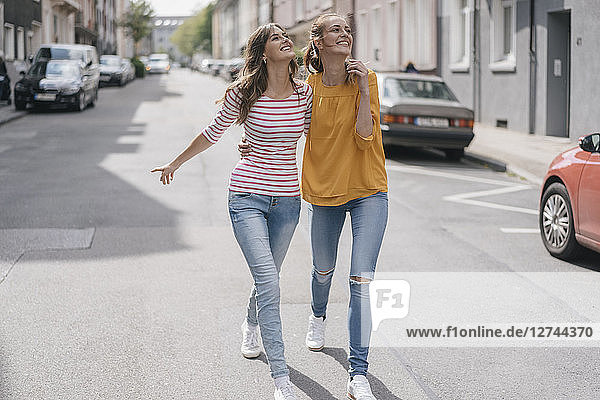 Two girlfriends having fun in the city  walking arm in arm