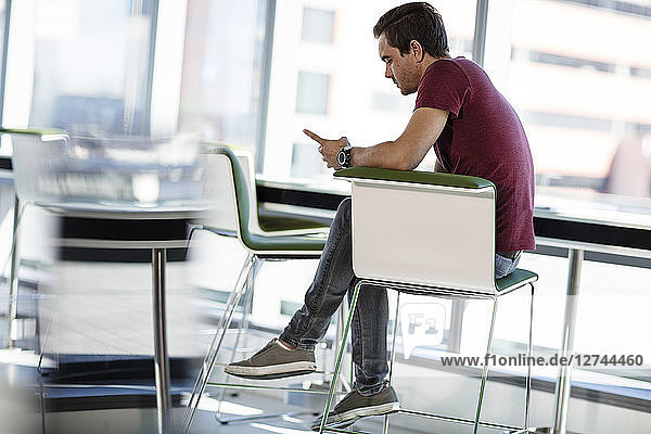 Businessman sitting in office  looking at smartphone