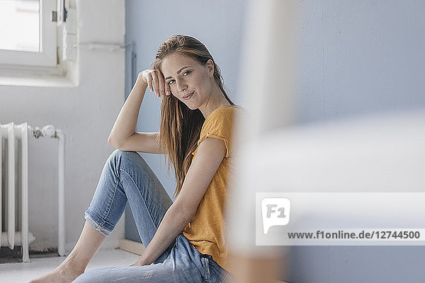 Smiling woman sitting on floor of her new home