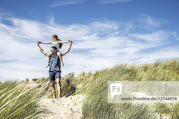 Netherlands  Zandvoort  father carrying daughter on shoulders in beach dunes