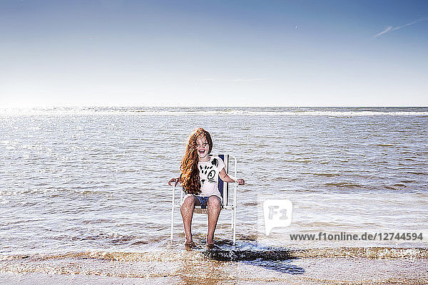 Netherlands  Zandvoort  happy girl sitting on chair in the sea