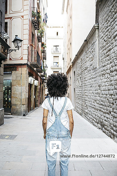 Spain  Barcelona  back view of woman with curly hair wearing dungarees