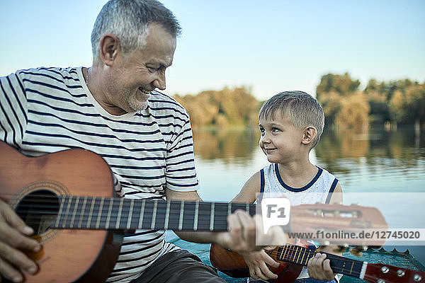 Grandfather teaching grandson playing guitar
