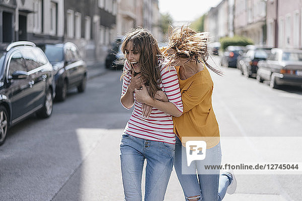 Two girlfriends having fun in the city  running