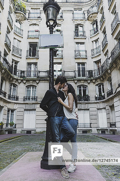 France  Paris  young couple in love standing at street lantern in front of urban building