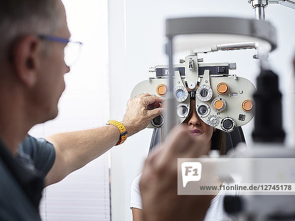 Optometrist examining young woman's eye