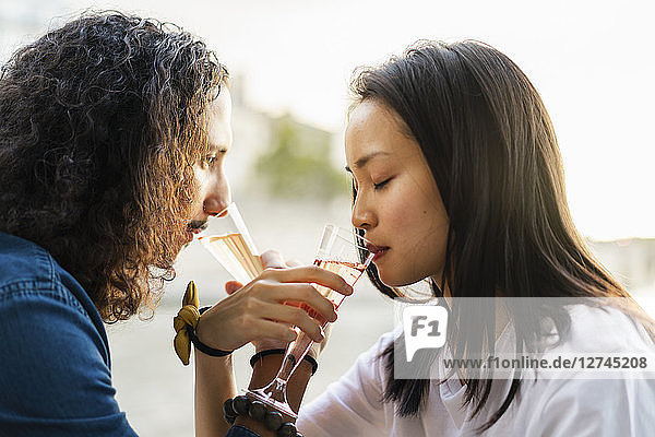 Young couple drinking champagne at the riverside